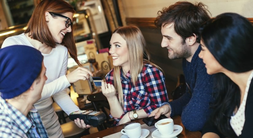 En gruppe unge mennesker som sitter rundt et bord på en kafe og snakker