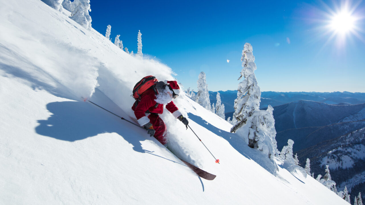 Mann i nissedrakt kjører på ski ned en fjellside. Foto