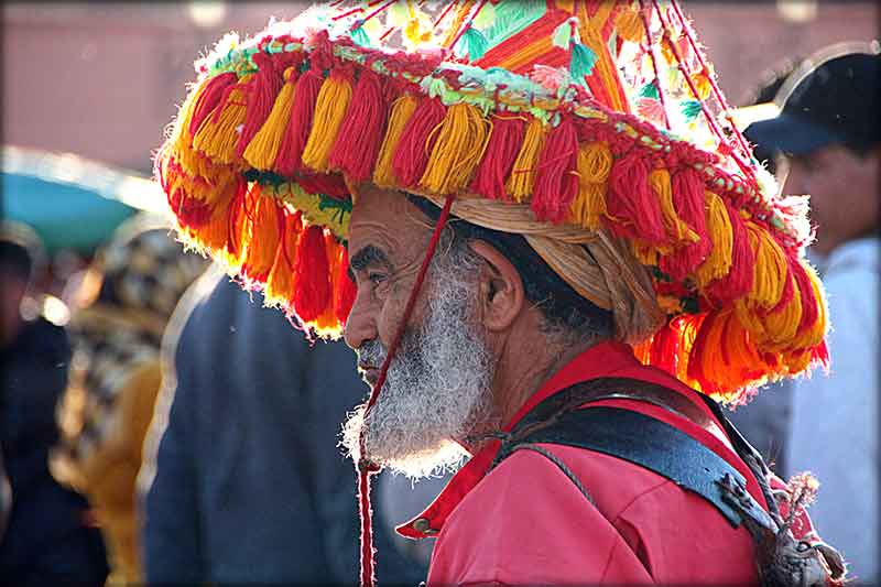 En mann med en stor tøyhatt full av farger i Marrakech
