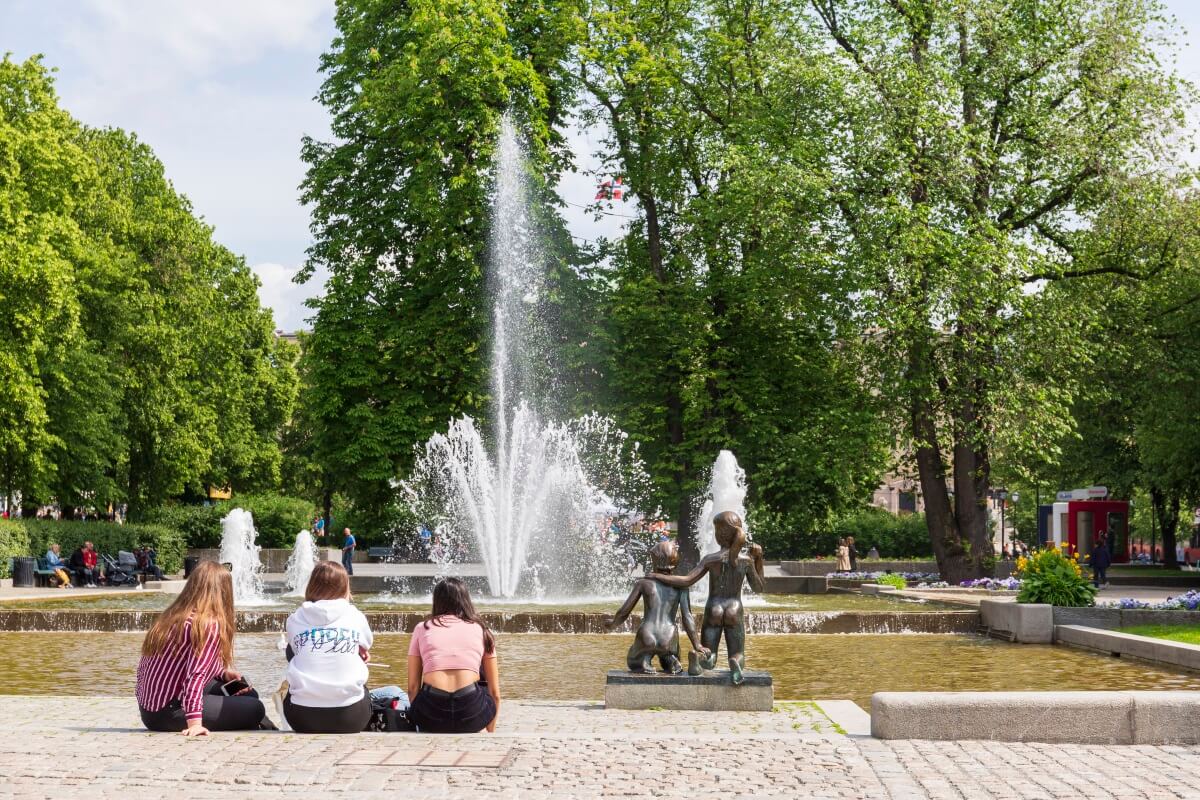 Jenter som sitter foran fontenen i Spikersuppa en sommerdag
