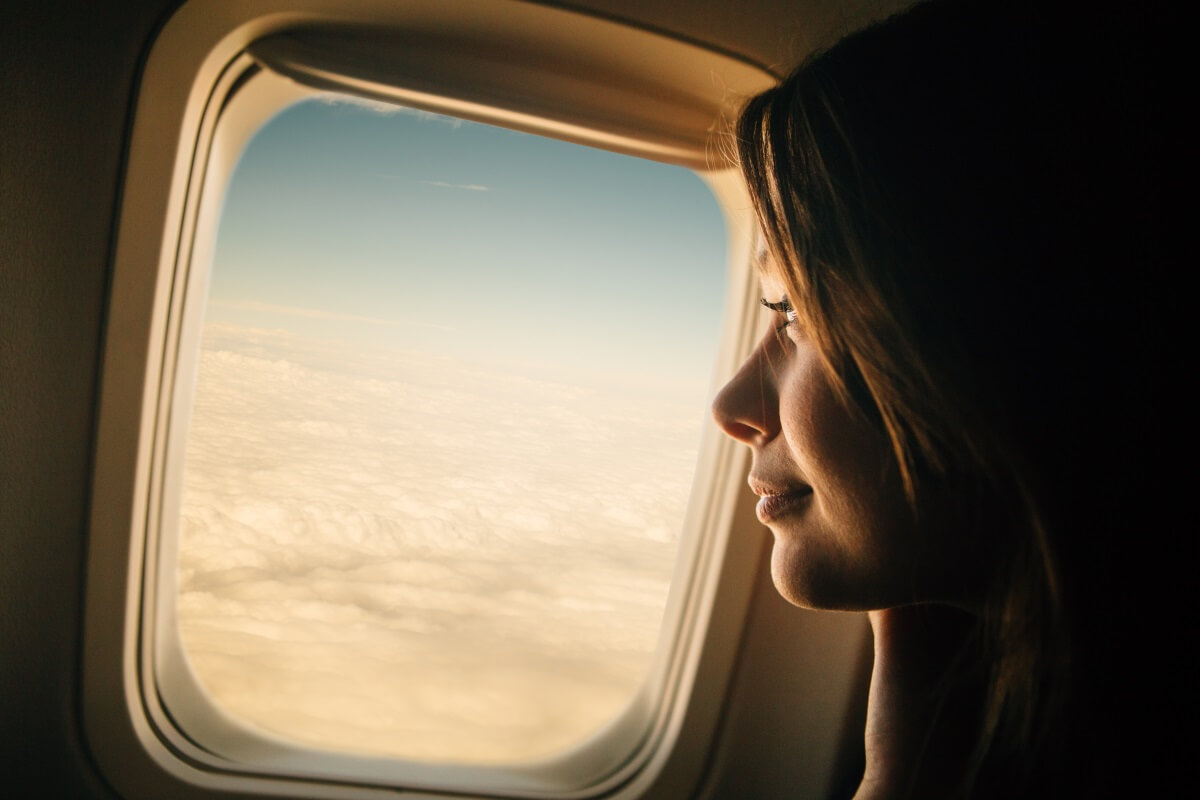 Kvinne ser ut av et vindu ombord et fly