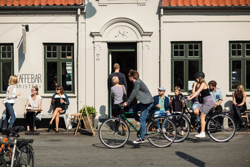 Stemning ved kaffebar og mann som sykler forbi i Latinerkvarteret, Århus