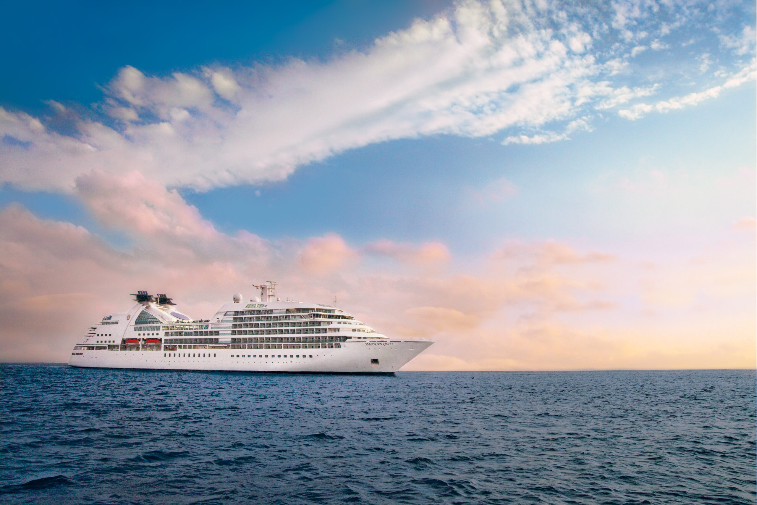 Et Seabourn-cruiseskip på havet med rosa himmel i bakgrunnen. Foto.