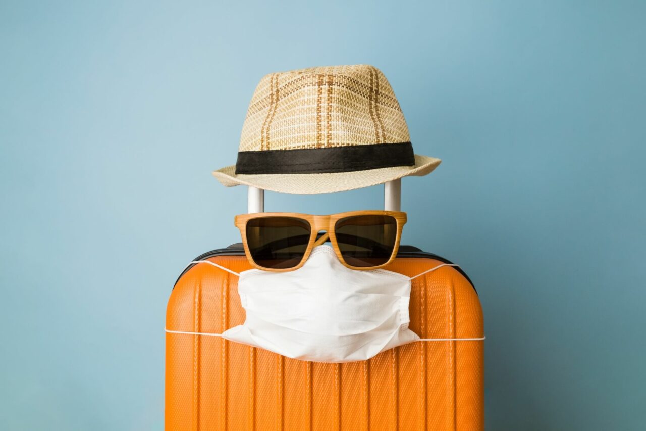 Koffert med hatt, solbriller og munnbind