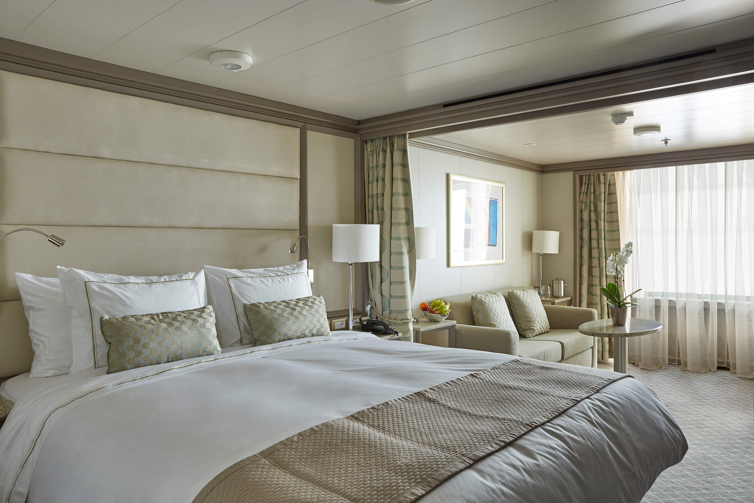 Bilde av seng og oppholdsrom i en suite om bord på Silver Muse. Foto.