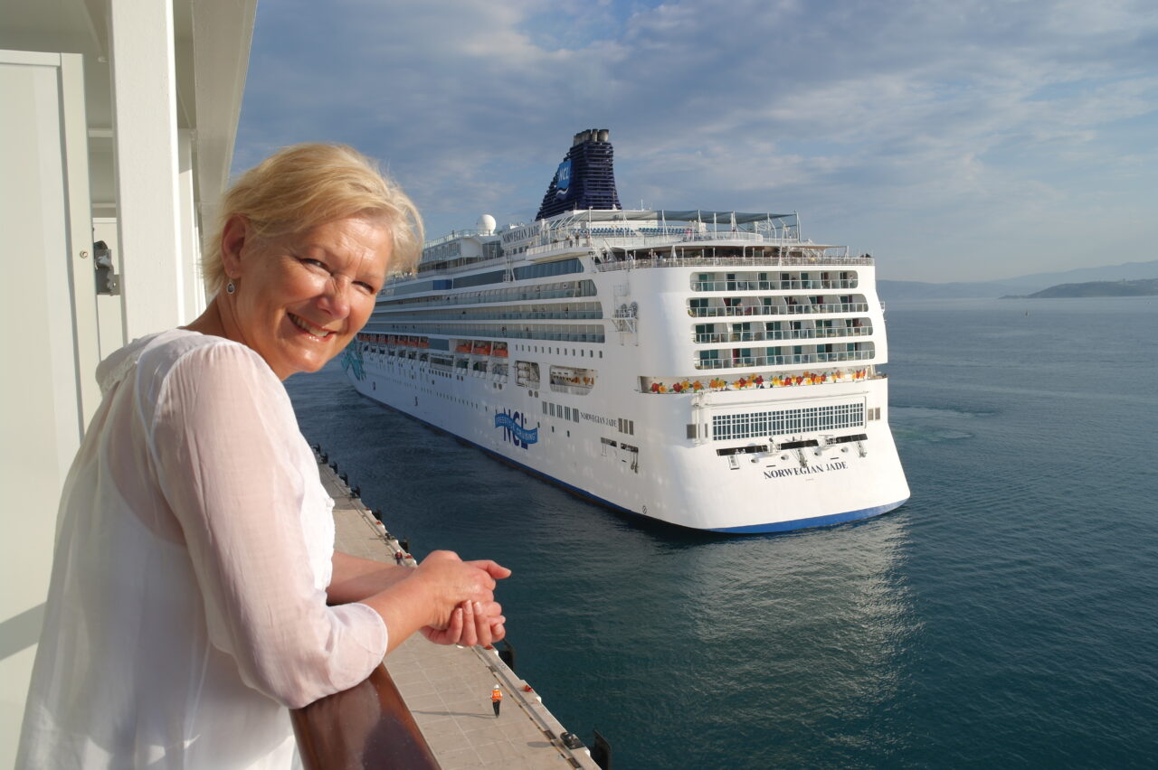 Elisabeth M. Bråthen i Berg-Hansen Cruise Collection på en lugarbalkong, med et annet cruiseskip i bakgrunnen. Foto.