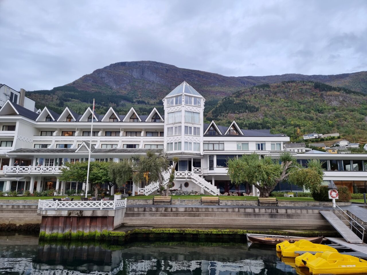 Stort hvitt hotell beliggende ved fjord. Foto