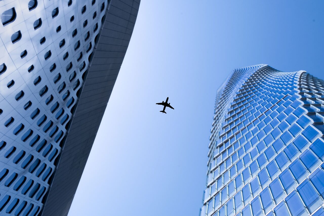 Fly sett fra bakken som flyr mellom høye bygninger