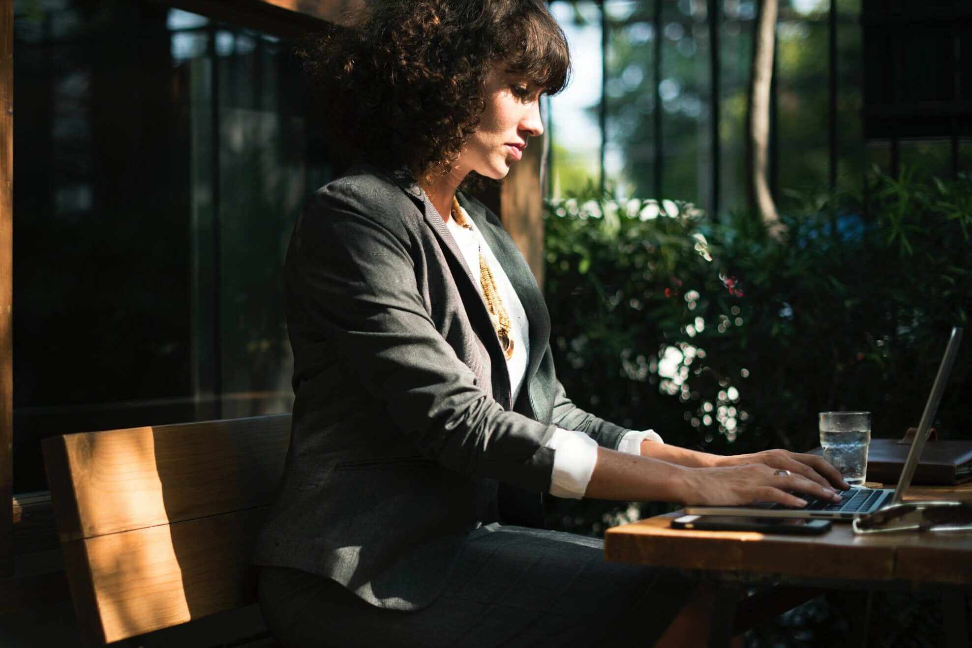 Kvinne sitter utendørs på kafe og jobber på PC
