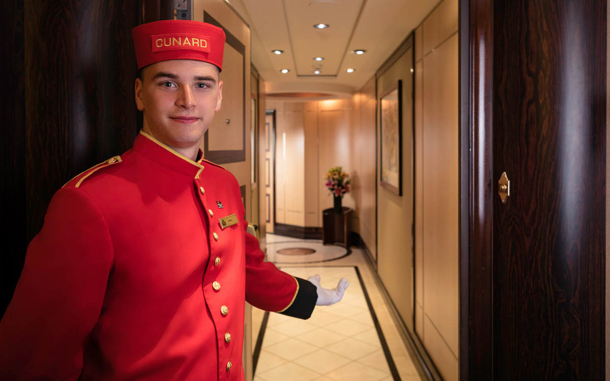 En bellboy ønsker velkommen til suiteområdet om bord på Queen Mary 2, Cunard. Foto.