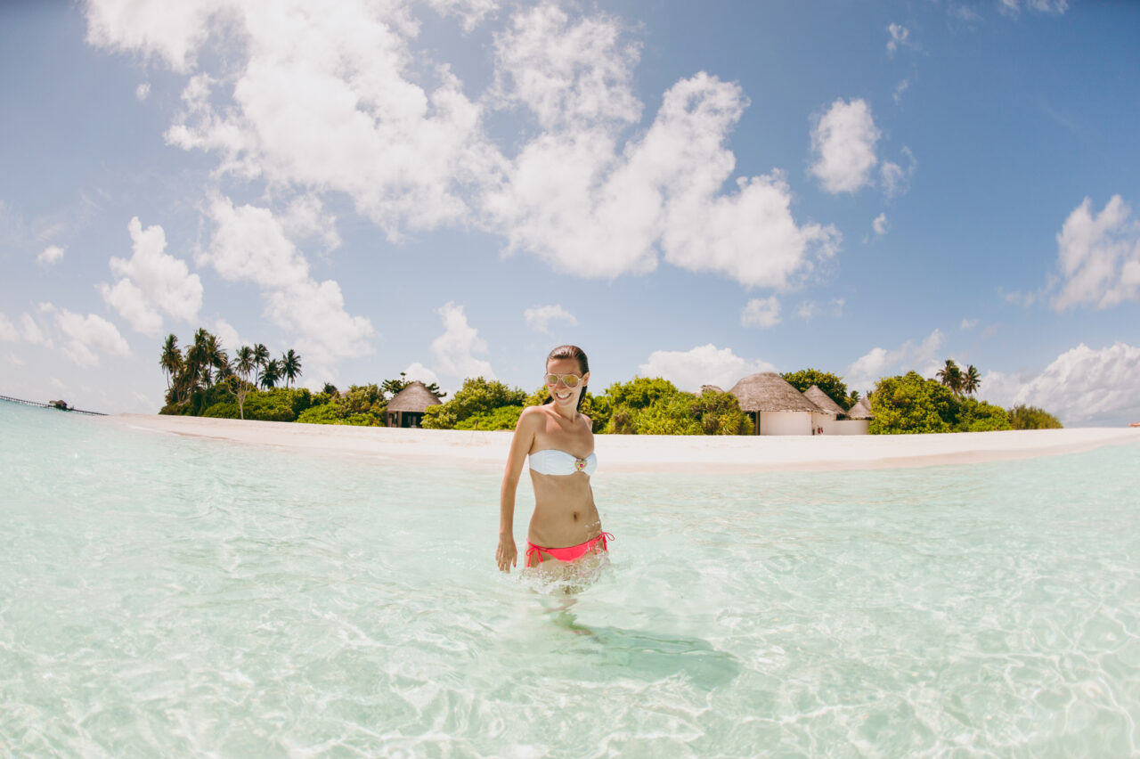 En jente bader i krystallklart vann på en vakker sandstrand