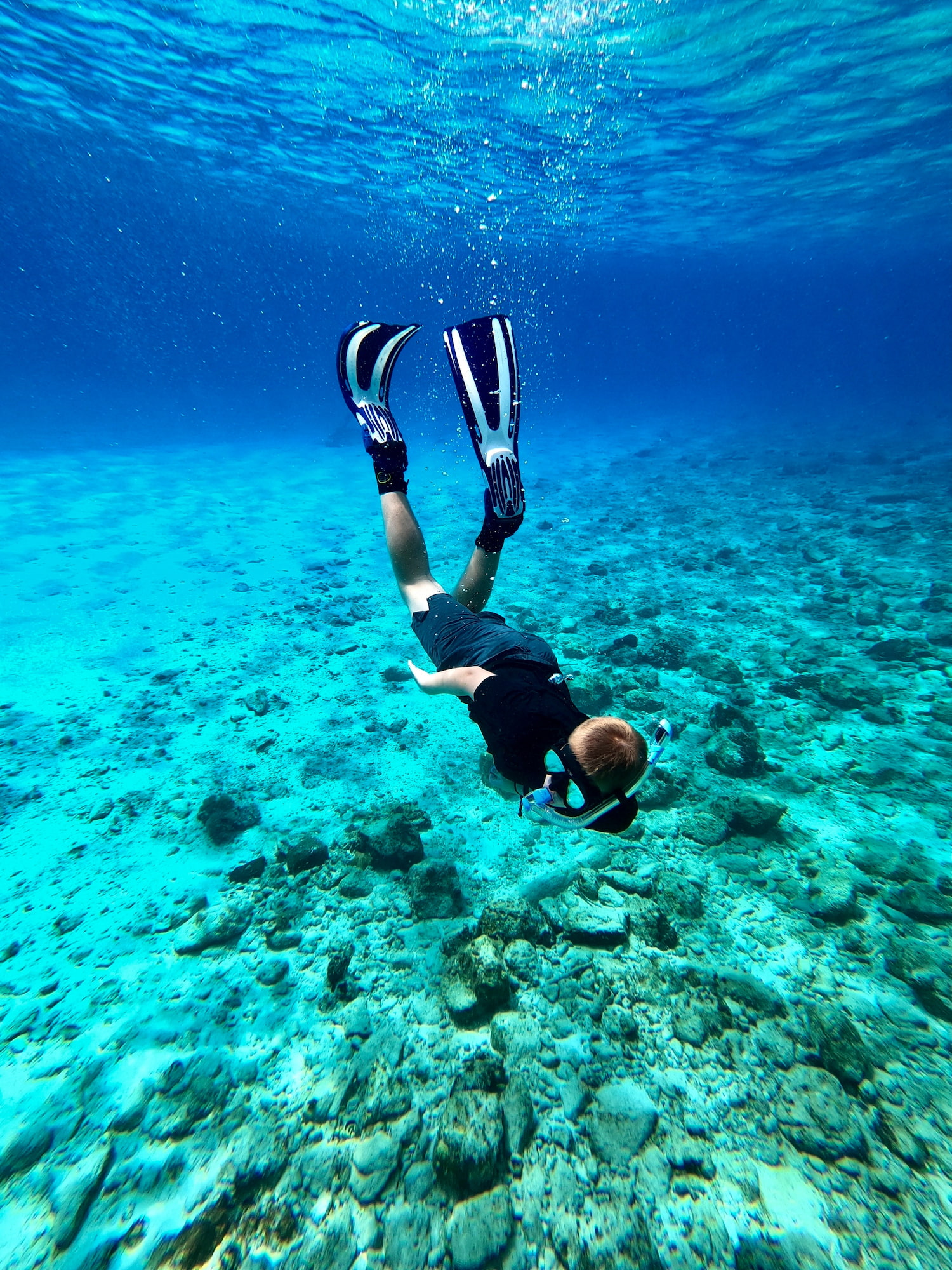 En mann som dykker i klart, blått vann. Foto