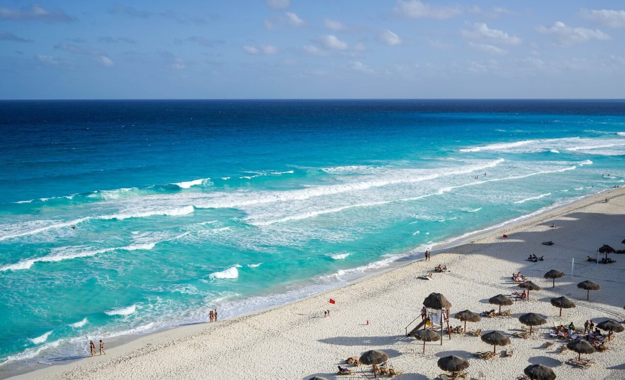Strand med blått hav og solsenger. Foto