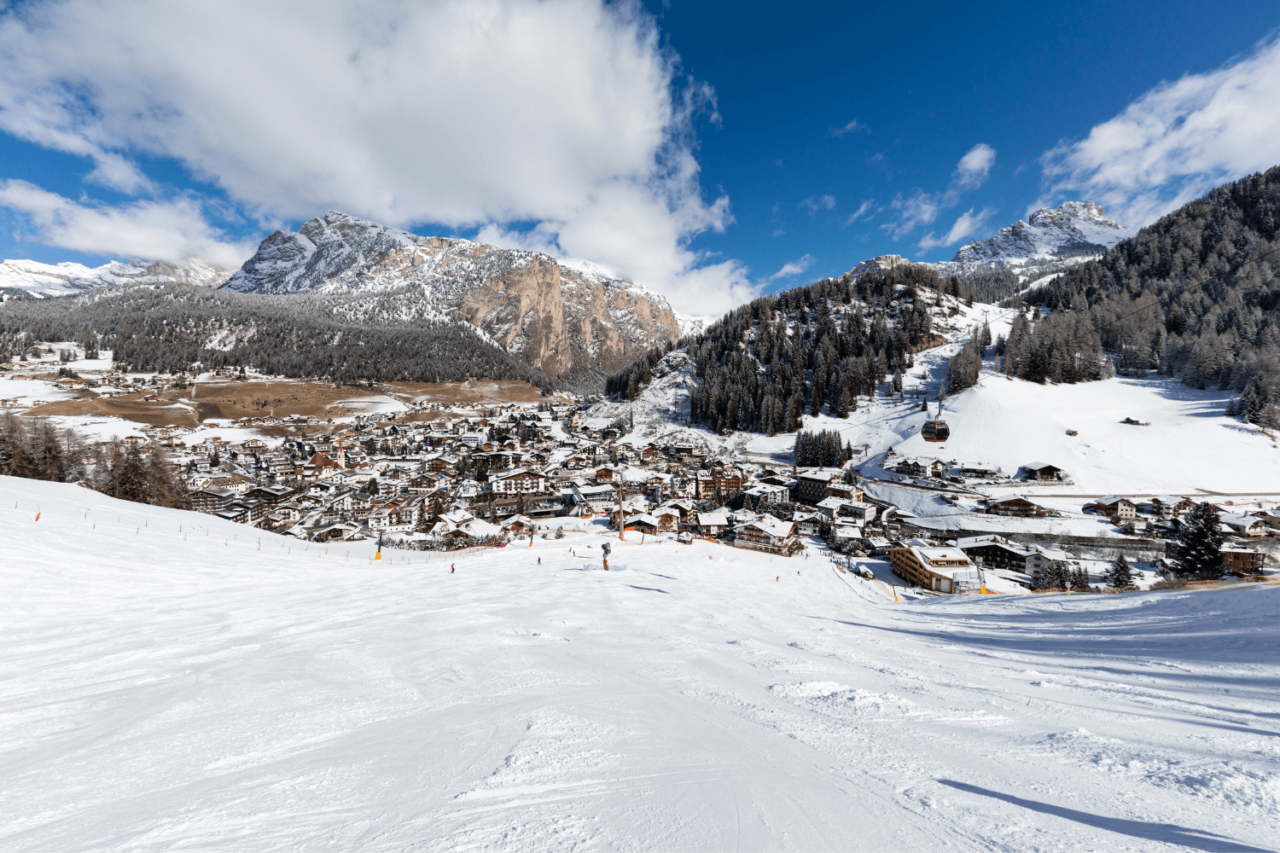 Slalåmbakke med snø som leder ned til landsbyen, Val Gardena. Foto
