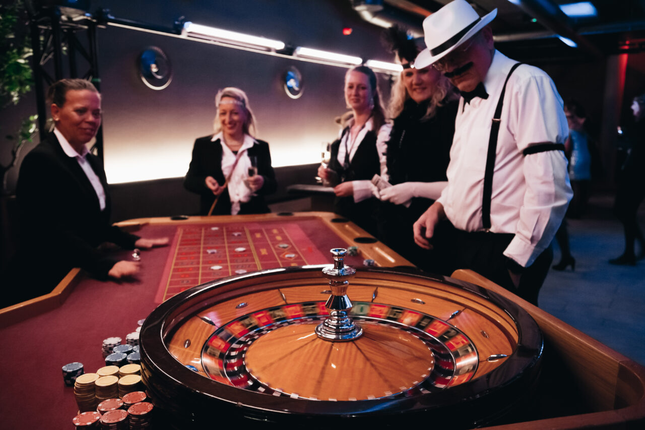 Fire mennesker kledd til fest står og spiller blackjack. Foto