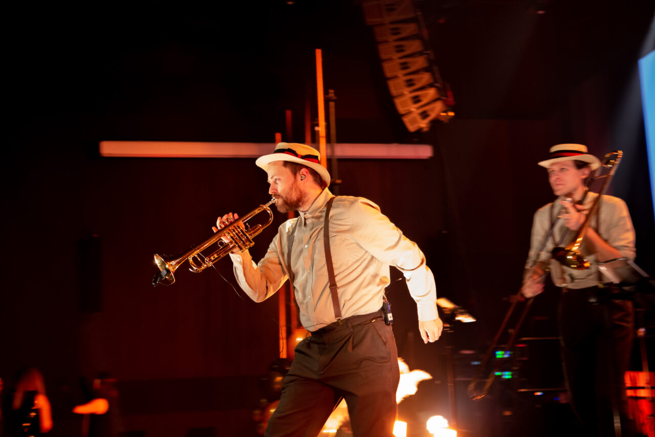 Mann med trompet står på scenen under underholder. Foto