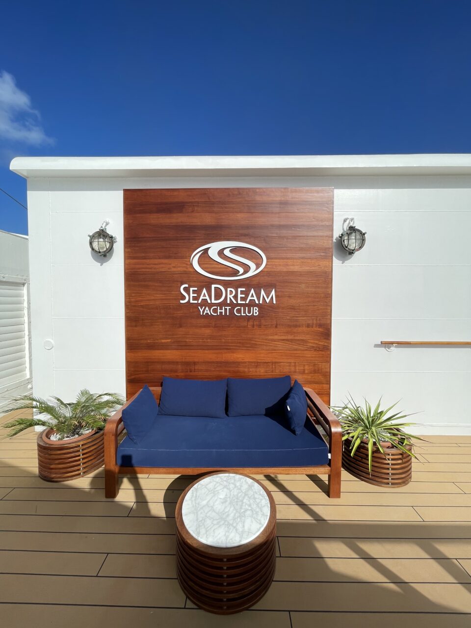 En blå sofa foran et skilt hvor det står "SeaDream Yacht Club". Foto.