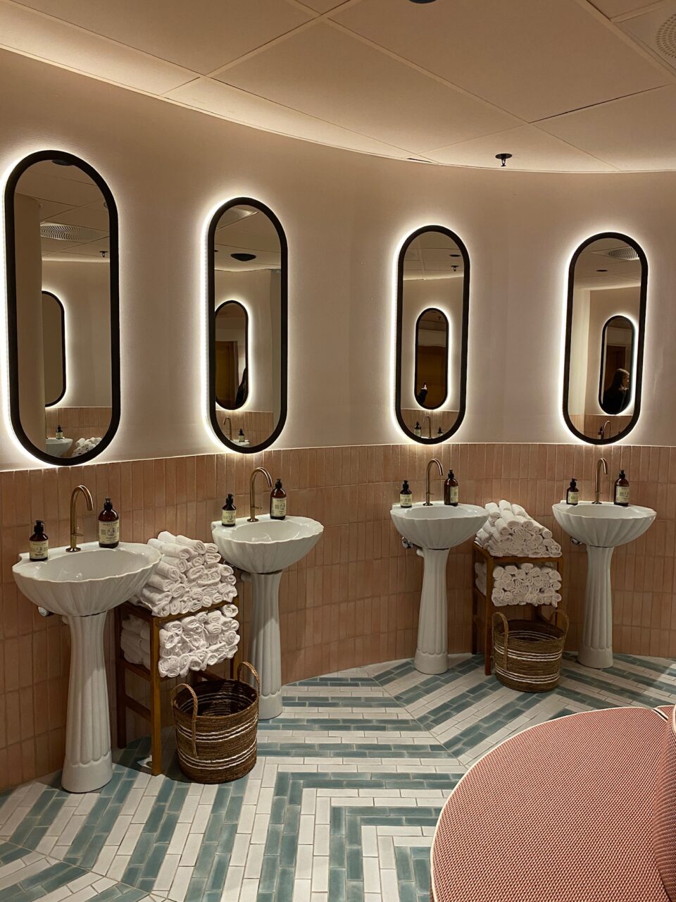 Vask og speil i en halvsirkel på et offentlig toalett. Foto