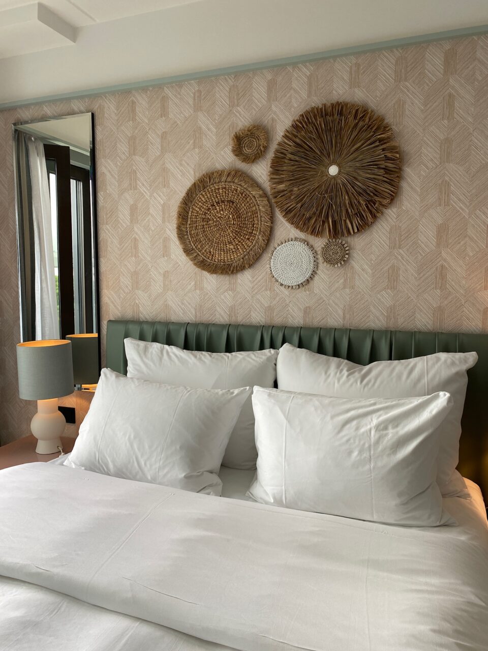 Hotellrom i duse farger med en dobbeltseng og dekor på veggen. Foto