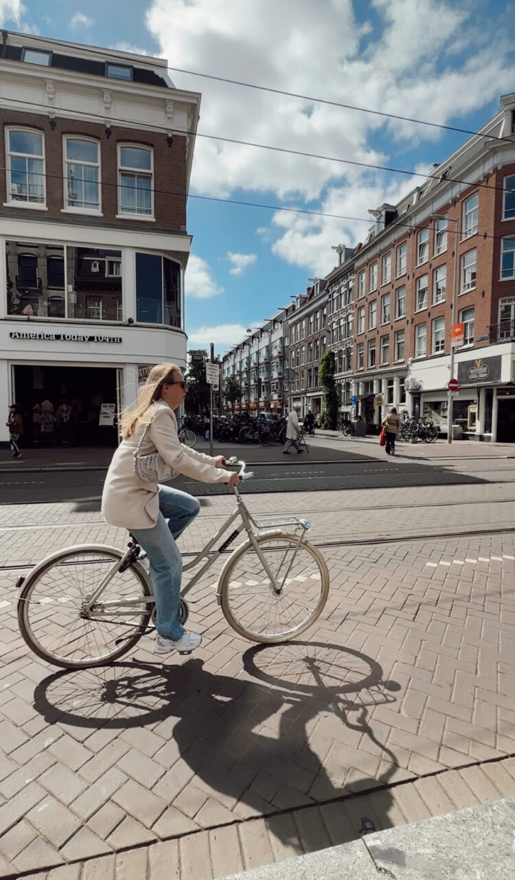 En kvinne som sykler i Amsterdam på en hvit sykkel. Foto