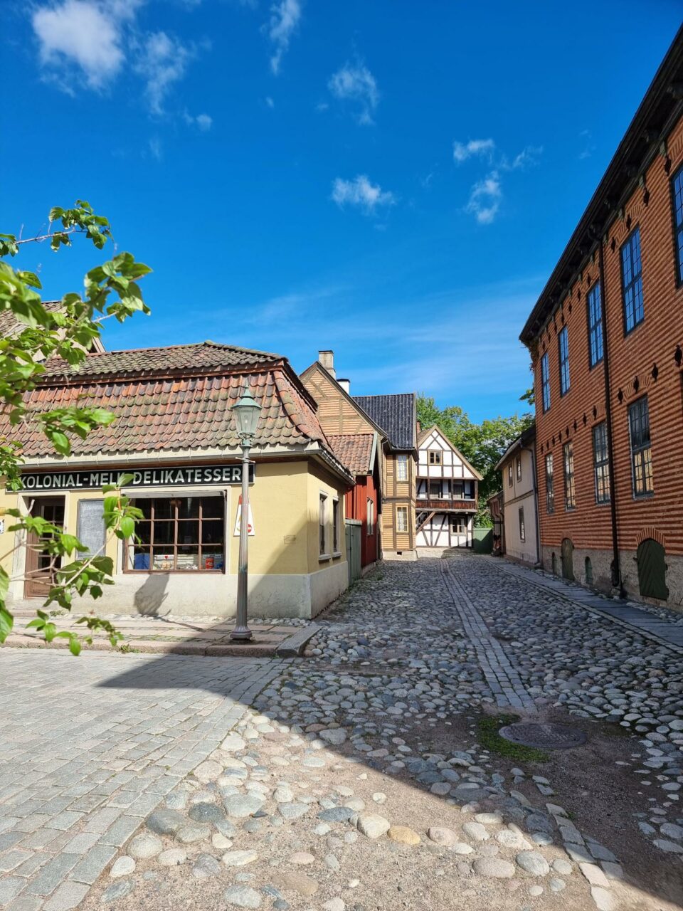 En bevart, gammel gate med brostein og gamle bygninger i murstein. Foto