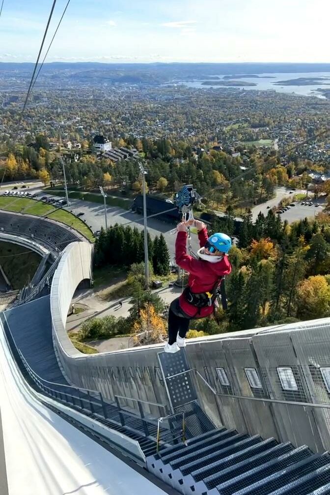En kvinne som tar zipline ned hoppetårnet i Holmenkollen. Foto