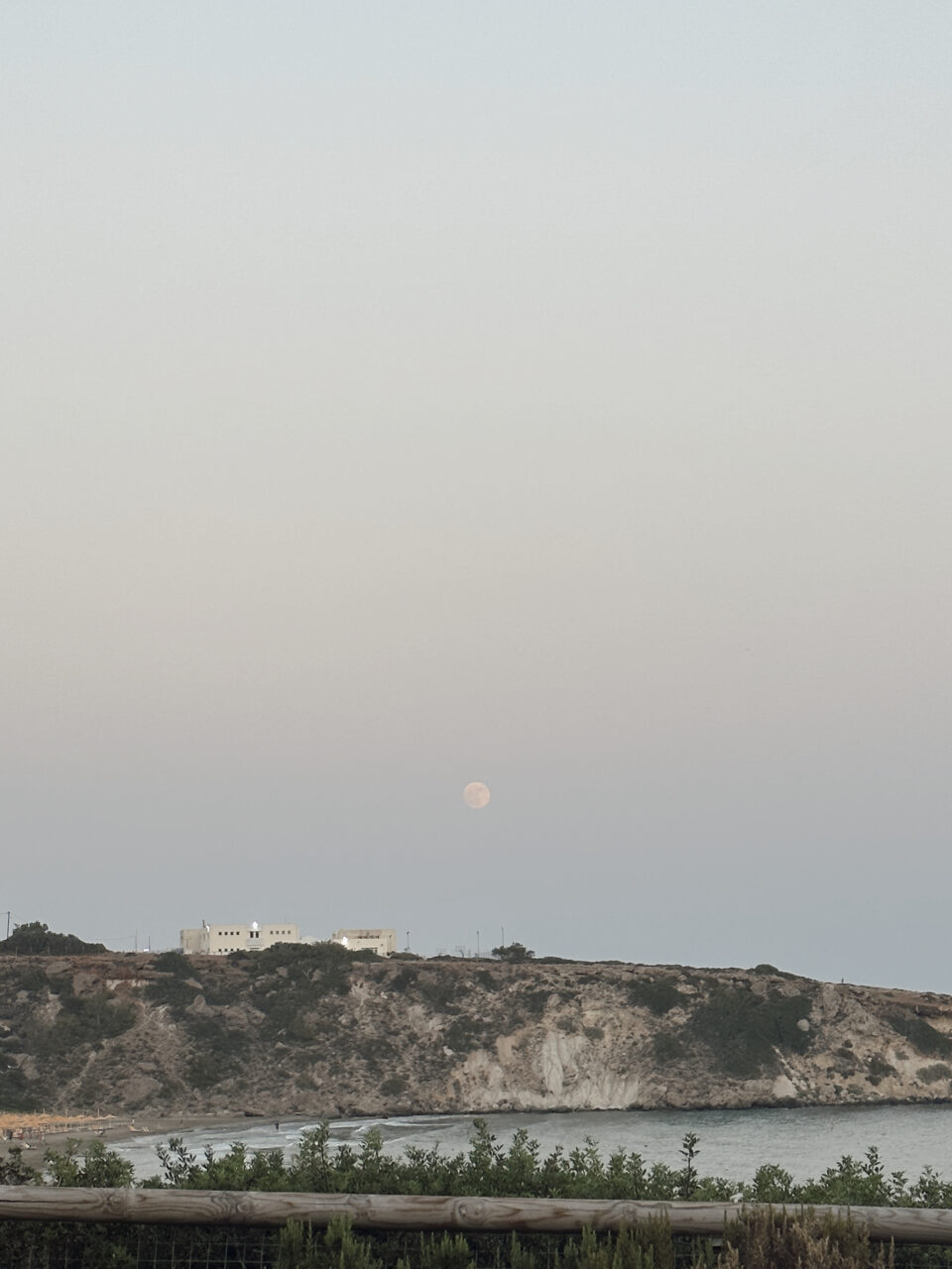 Utsikt mot havet der månen lyser over fjellet. Foto