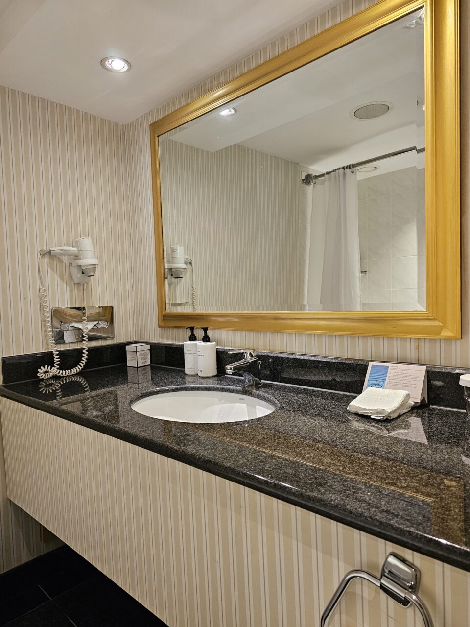 Bad med gullspeil, vask og badekar. Foto