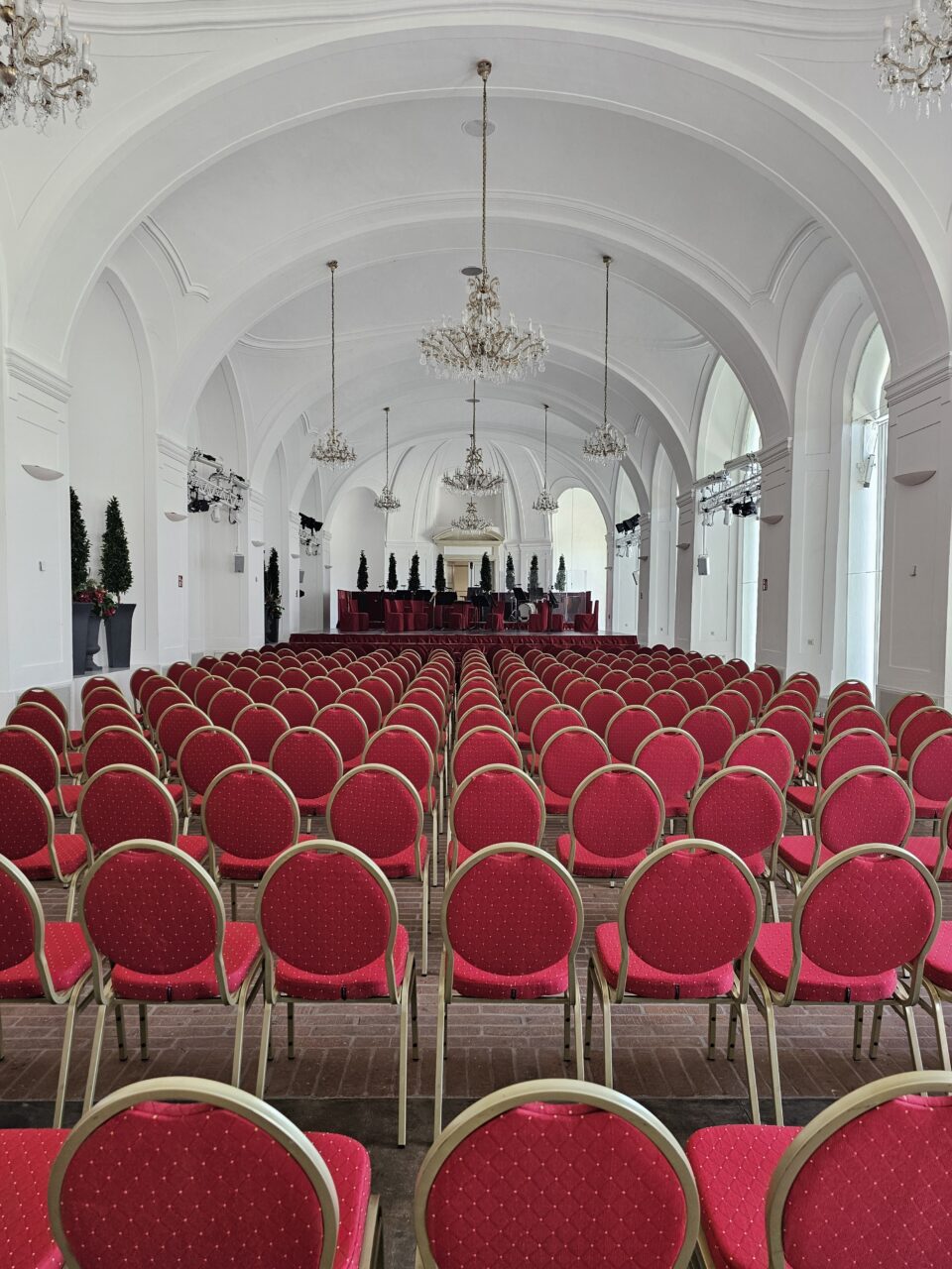 Stort hvitt konferanserom med røde stoler i kino-oppsett. Foto
