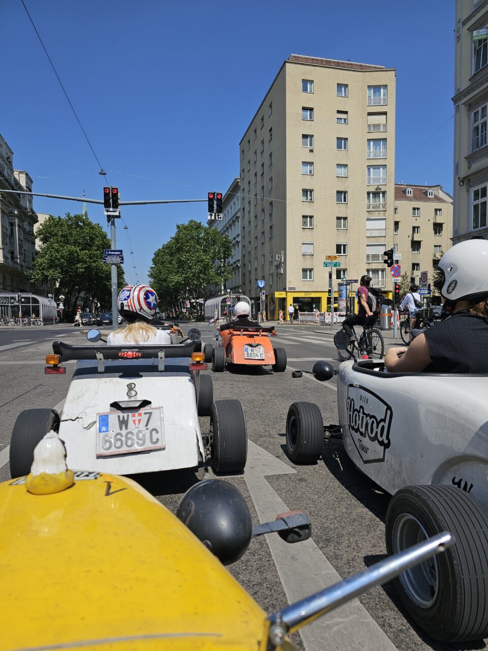 En liten gruppe kjører små fargerike biler i gaten. Foto