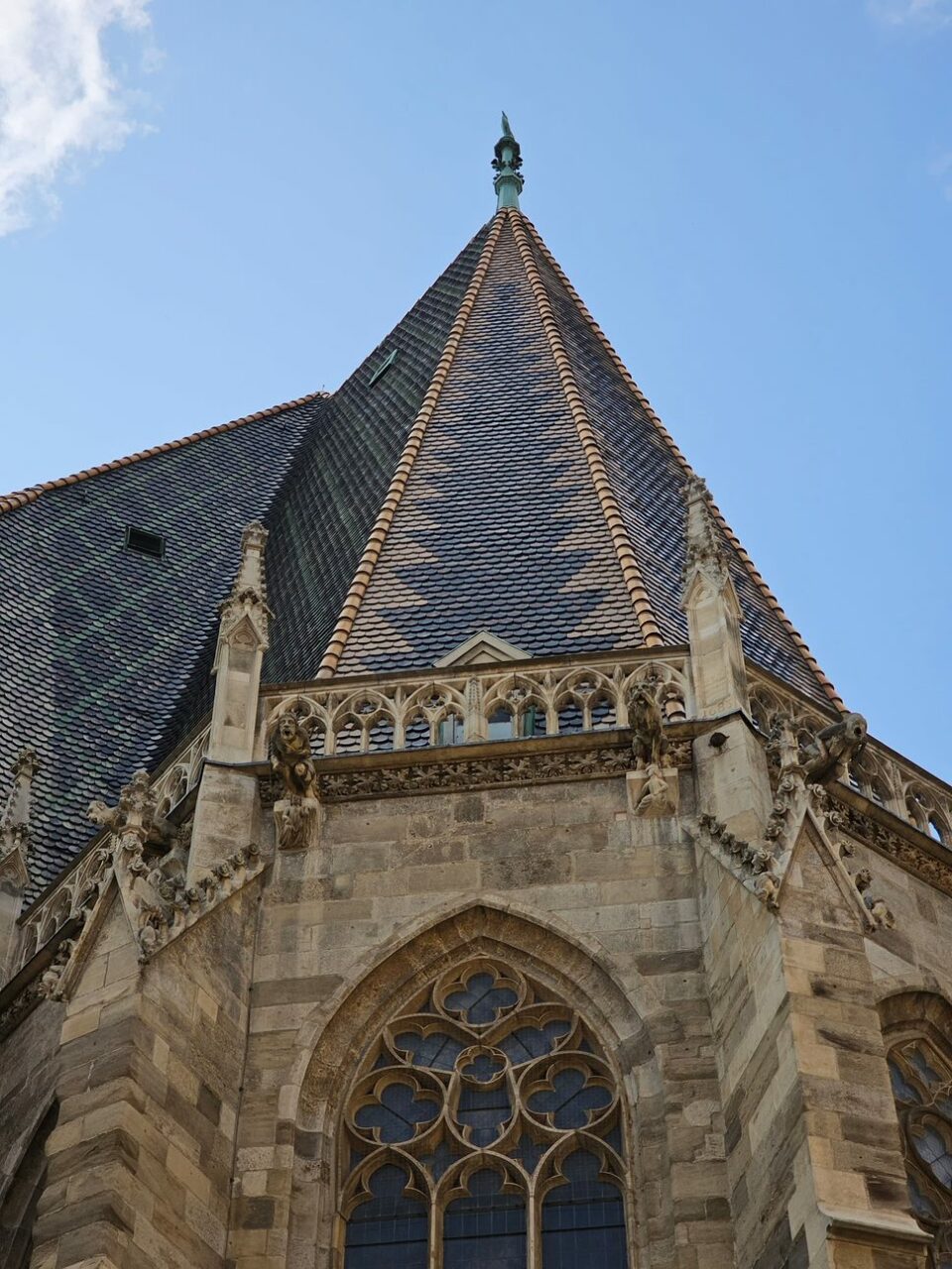 Bilde tatt tett på spiret på en kirke, hvor du ser rutete detaljer på taket. Foto