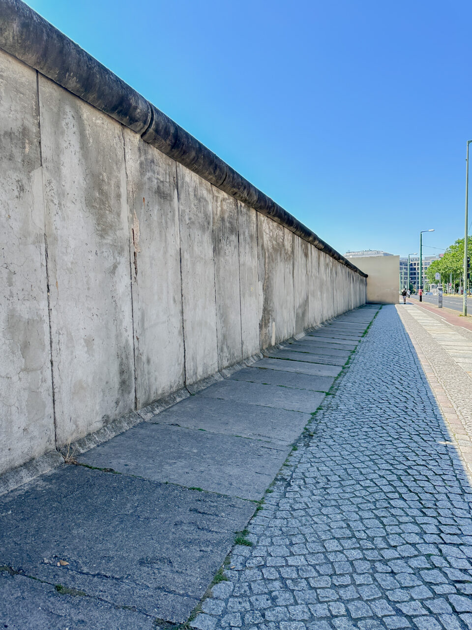 Berlinmuren som strekker seg nedover en gate. Foto