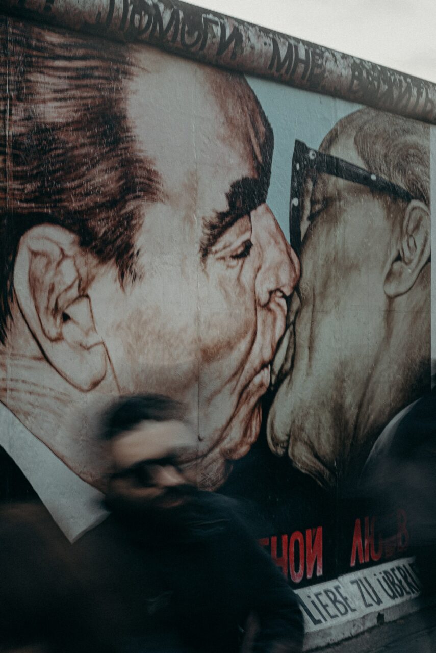 To menn som kysser malt på en murvegg. Foto