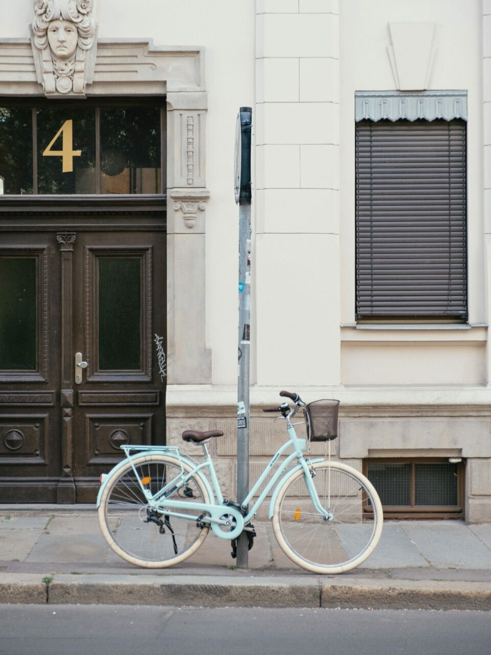 Sykkel parkert inntil en stolpe langs en ren gate. Foto