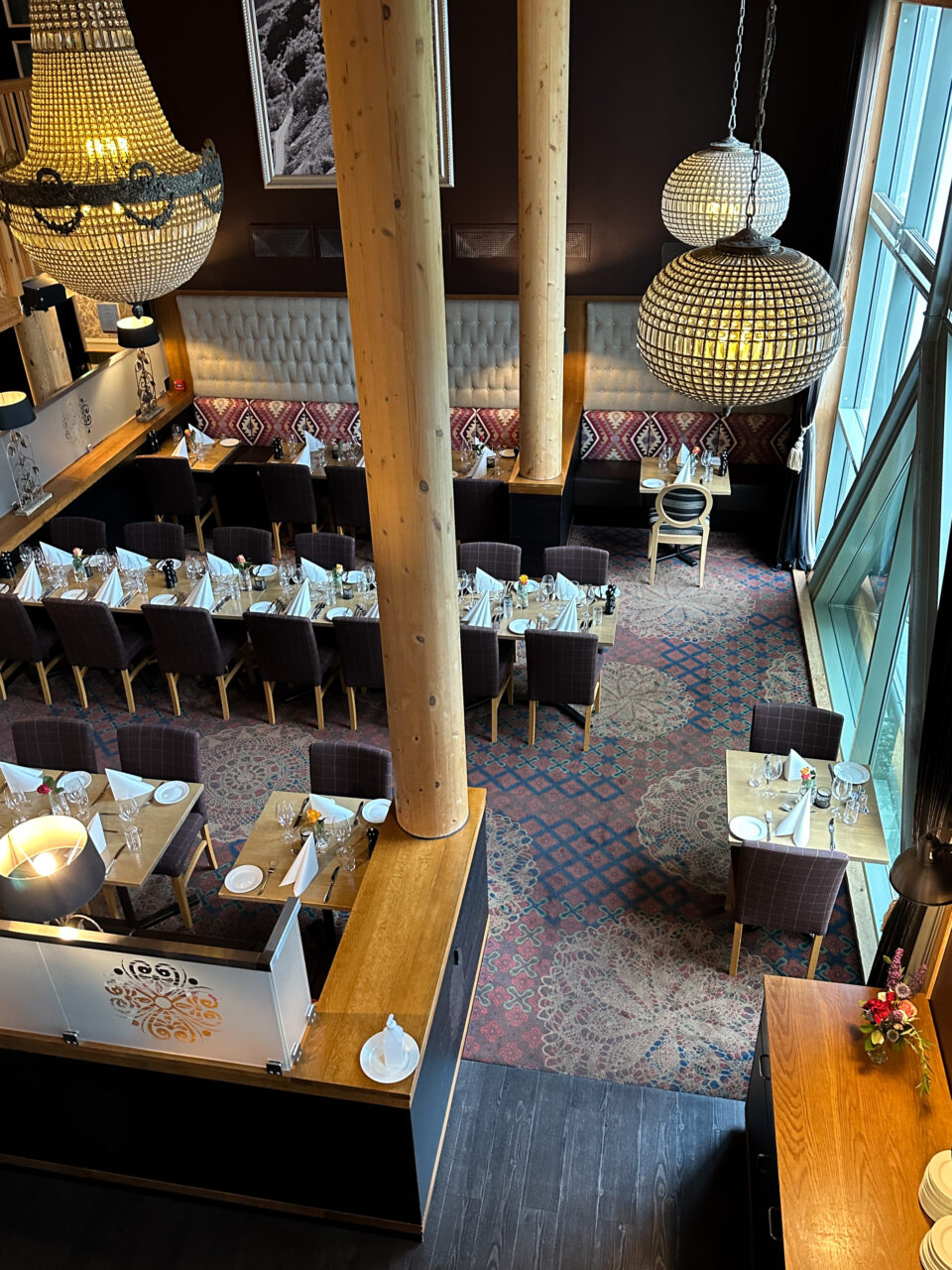 En restaurant med dekket bord og lysekroner i taket. Foto