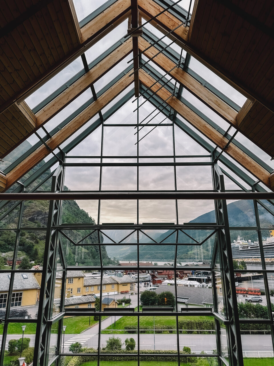 Et stort vindu formet som en trekant med utsikt mot fjell og fjord. Foto