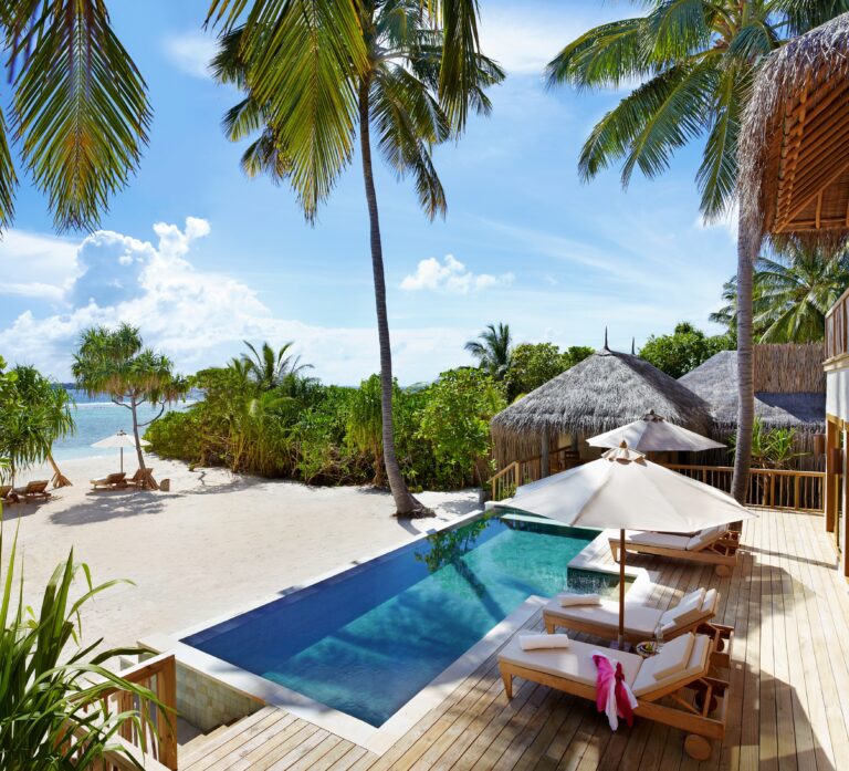 Privat svømmebasseng ved sandstrand og palmer. Foto