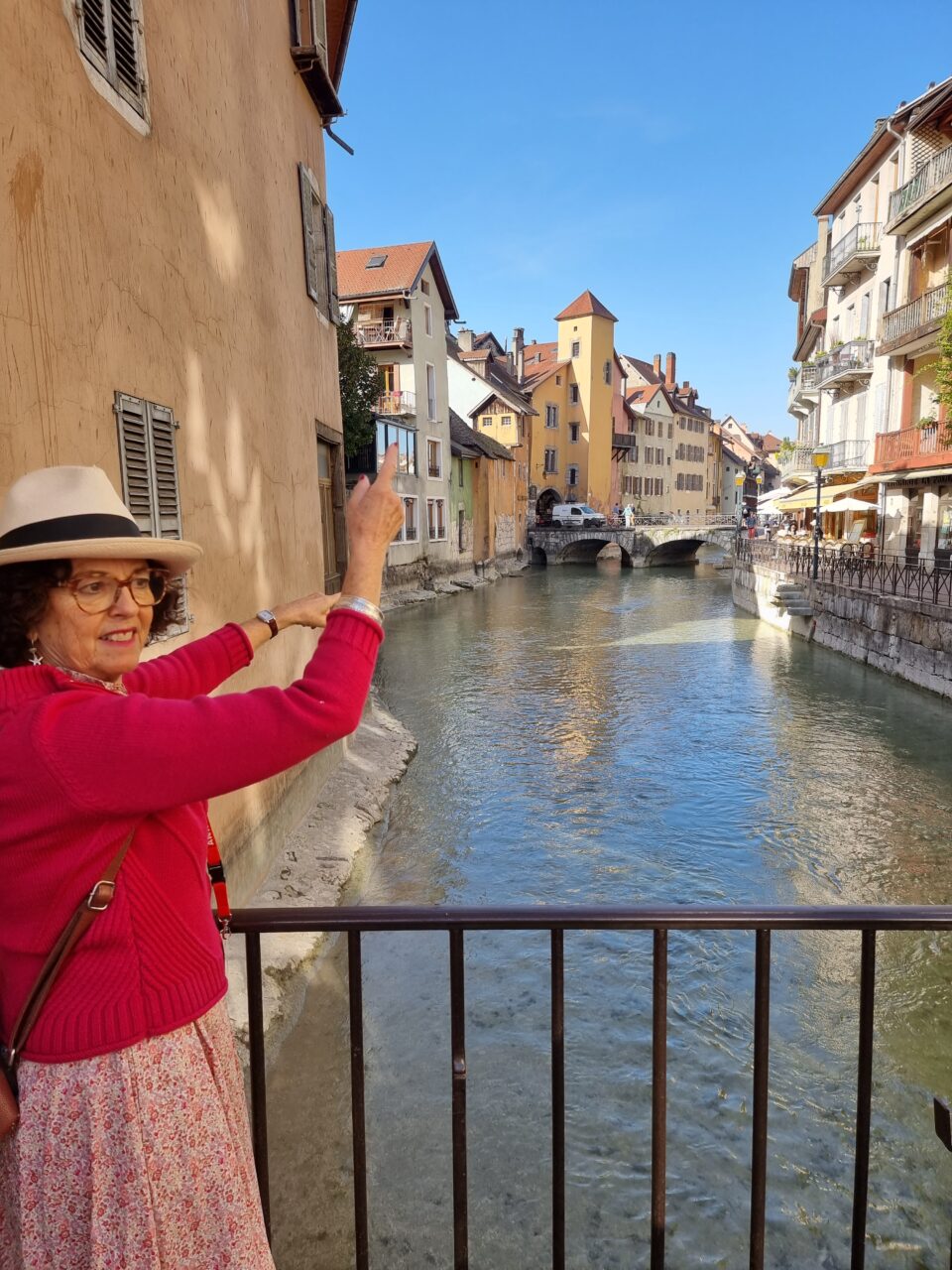 Kvinne står og viser frem en kanal omringet av hyggelige hus. Foto