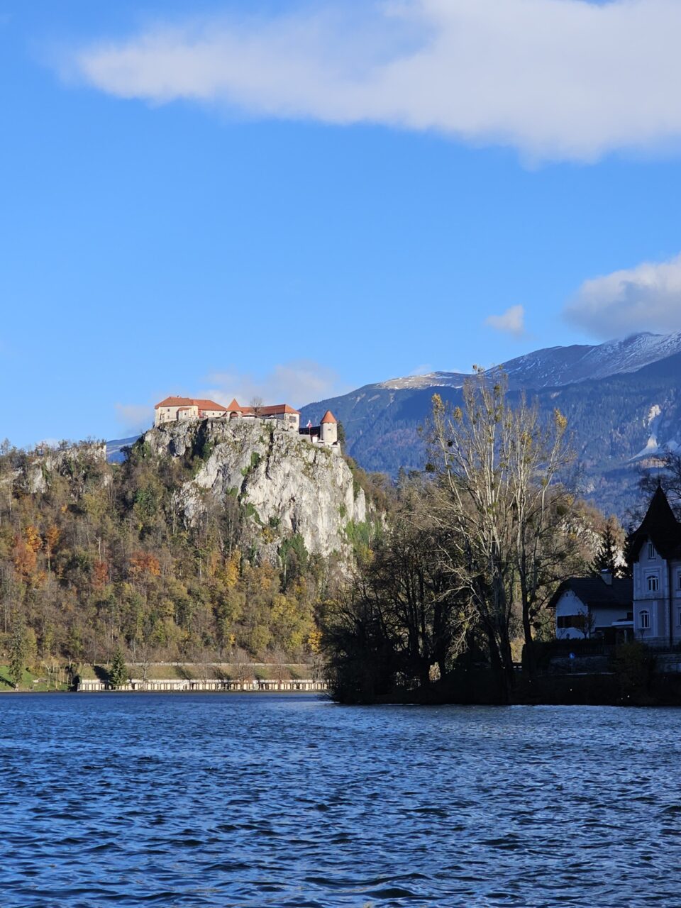 Slott beliggende oppe på en klippe over en innsjø. Foto