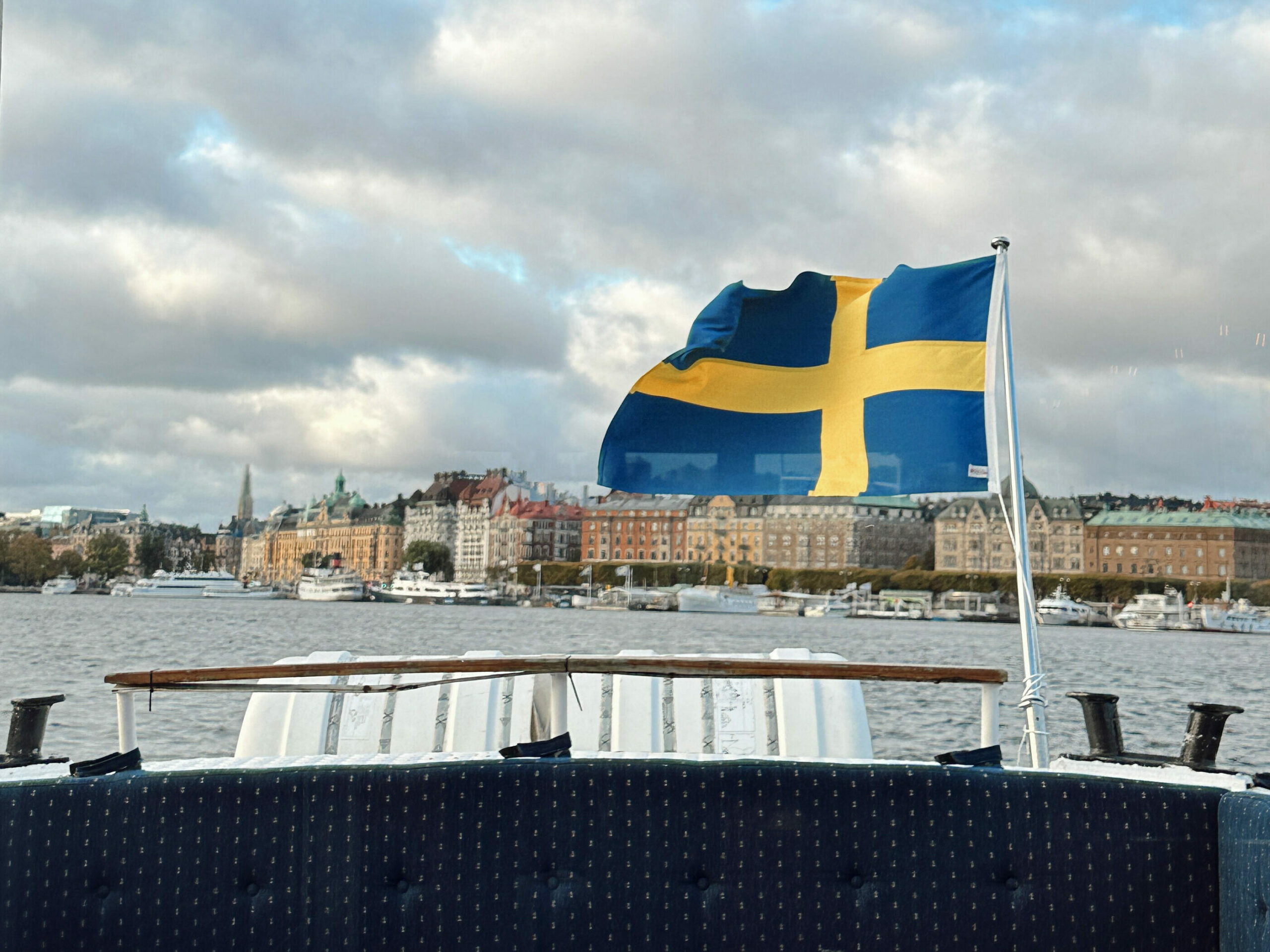 Svensk flagg som veier i vinden på baksiden av en båt. Foto