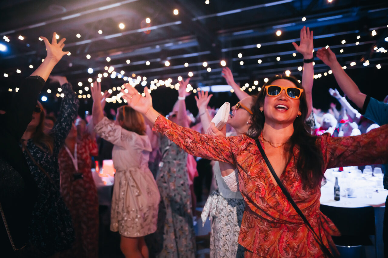 Kvinne med solbriller danser på jobbfest. Foto
