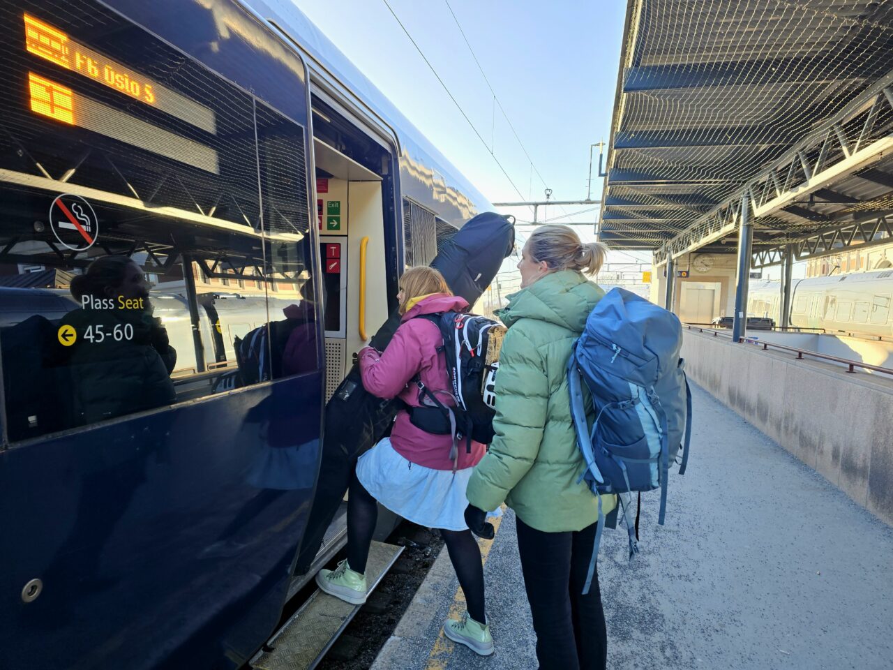 Turister med bagasje på vei inn på tog. Foto