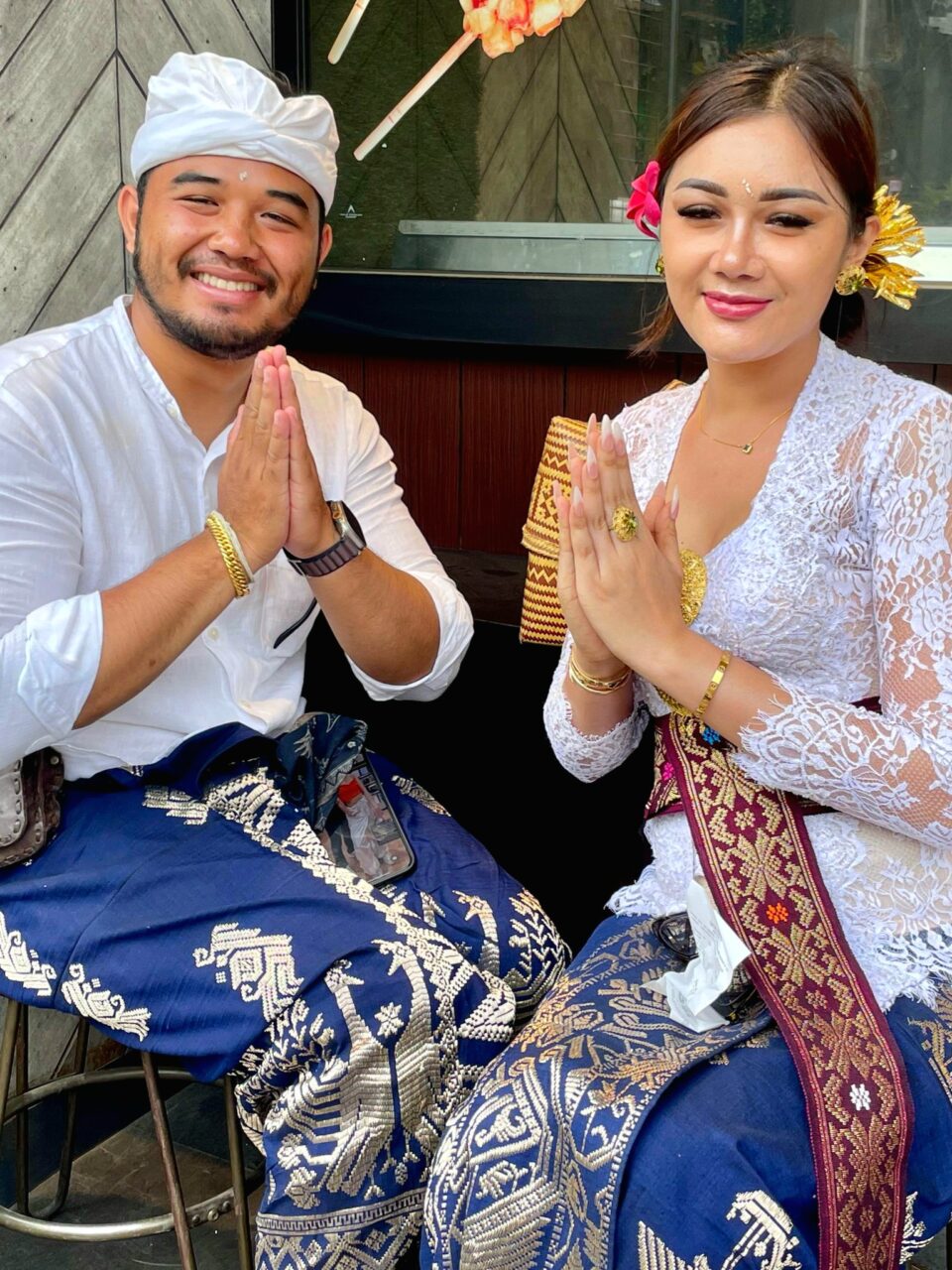 To balinesere løfter hendene og smiler inn i kamera. Foto