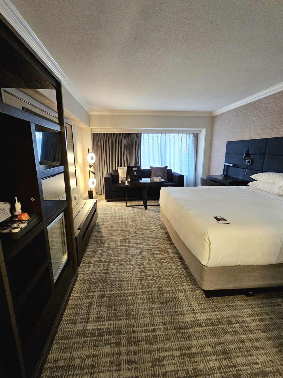 Stort hotellrom med stor dobbeltseng og lyse flater. Foto