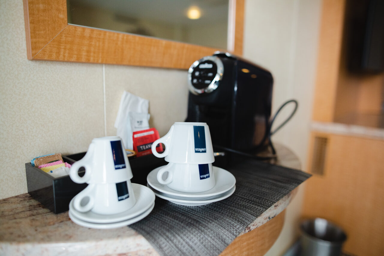 Kaffemaskin og kopper med te og kaffe på et bord. Foto