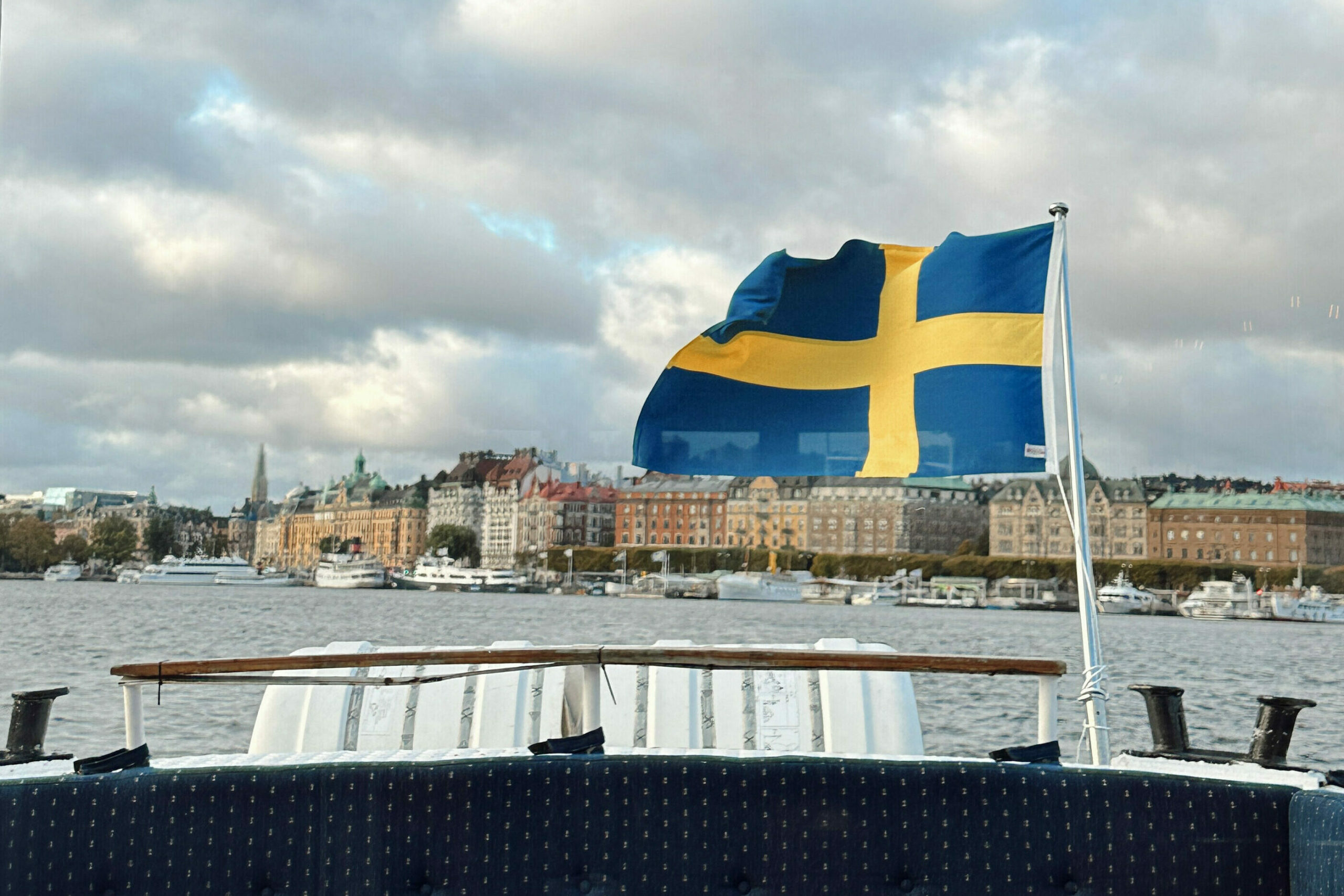 Svensk flagg som veier i vinden på baksiden av en båt. Foto