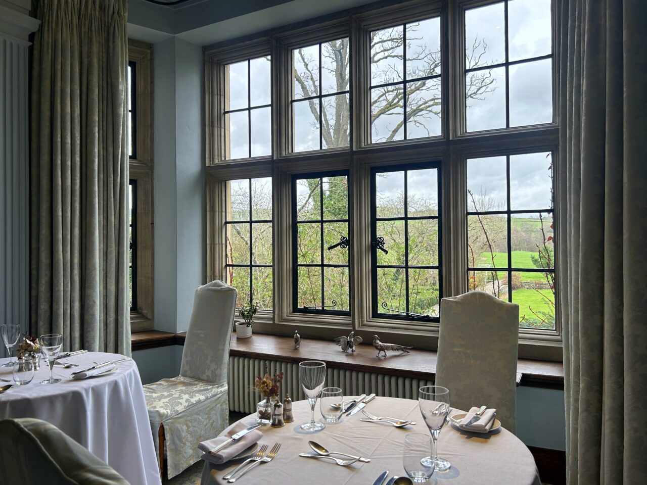 Spisesal med hvite duker og grønn utsikt. Foto