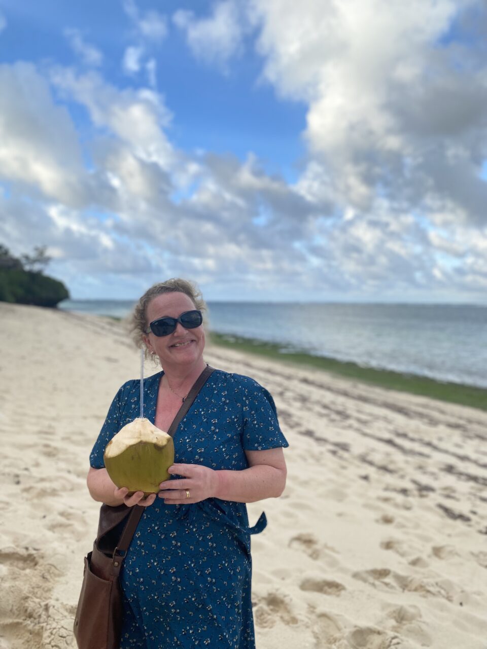 Kvinne med kokosnøtt på stranden. Foto