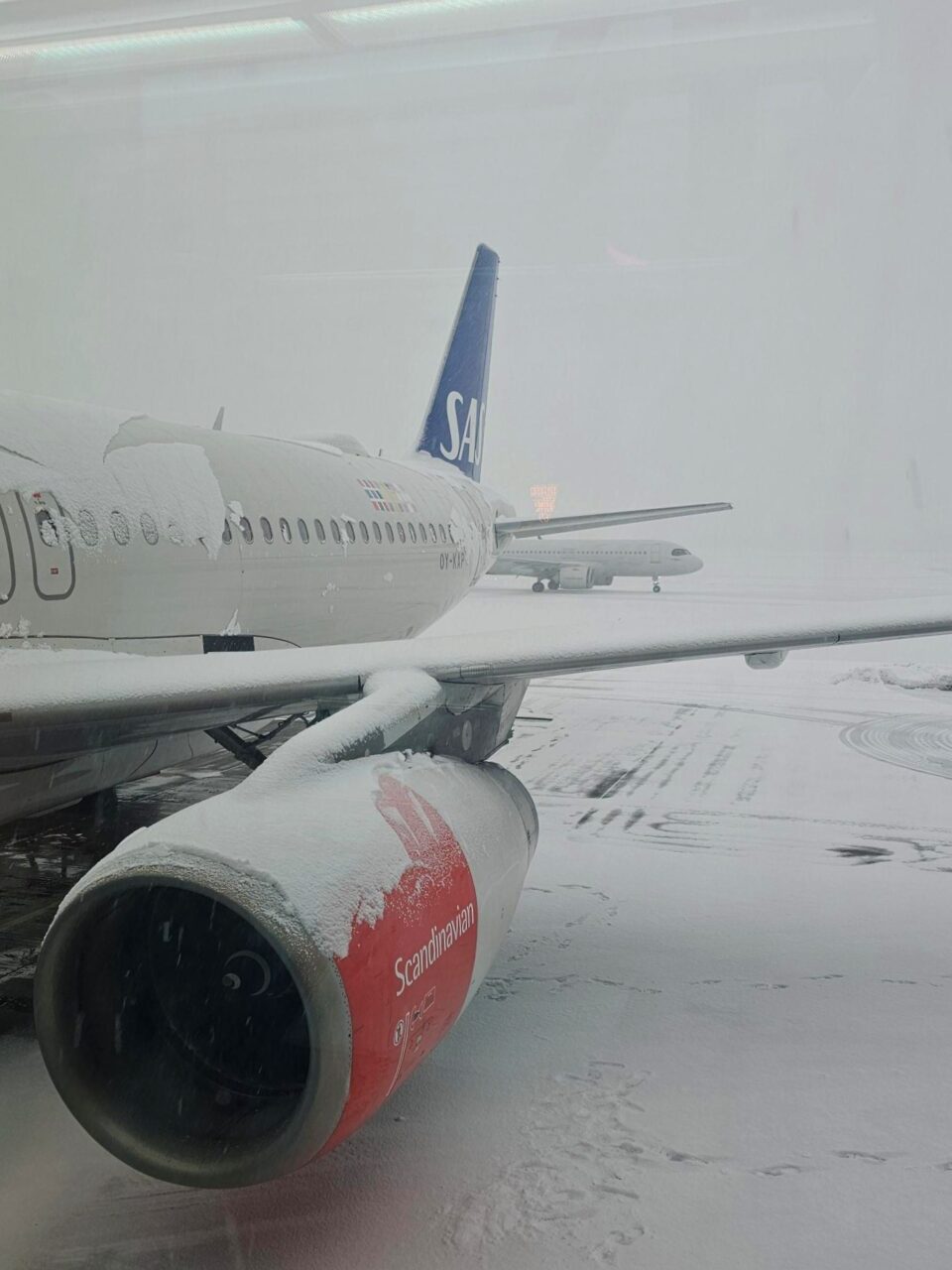 Fly med masse snø på seg står parkert. Foto