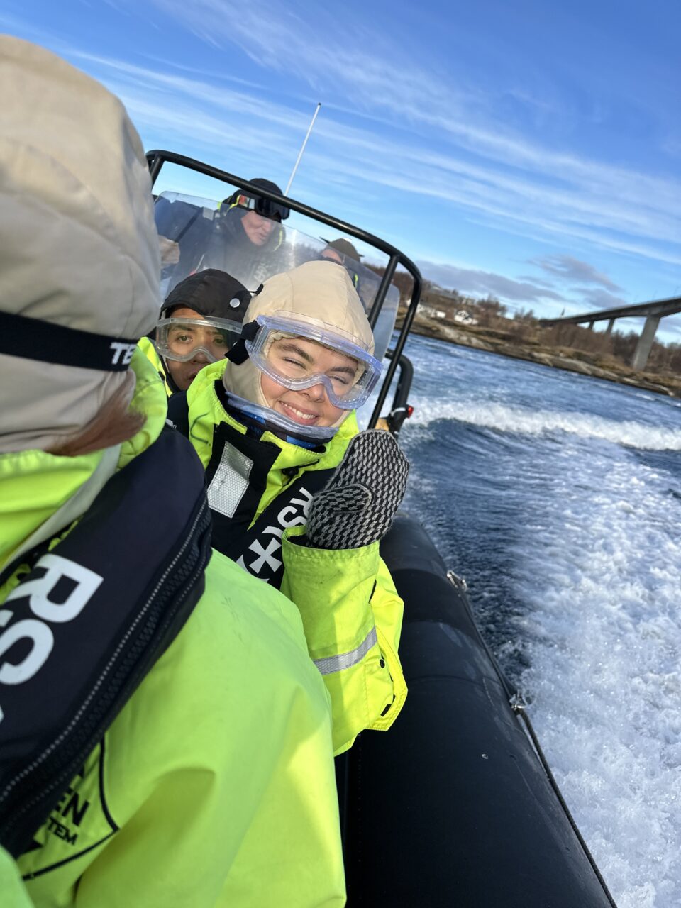 Glade mennesker sitter på en RIB som kjører fort på fjorden. Foto